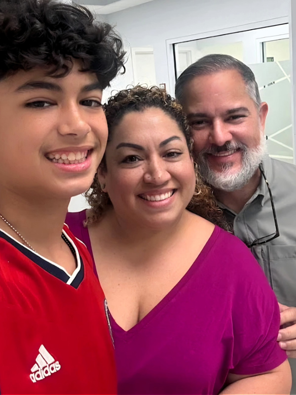 Teen patient smiling with his mother and Dr. Martinez after braces removal at the Miami orthodontic office.