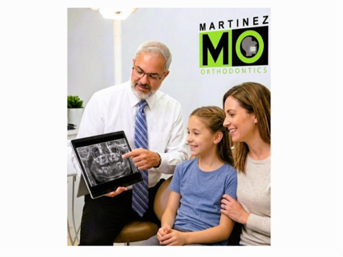 Dr. Martinez in Miami reviewing a digital panoramic X-ray with a patient to evaluate dental development.